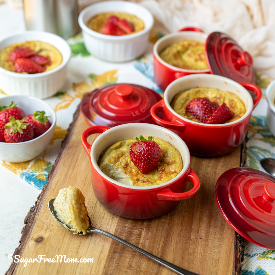 Sugar free low carb keto coconut custard baked in red ramekins topped with fresh strawberries.