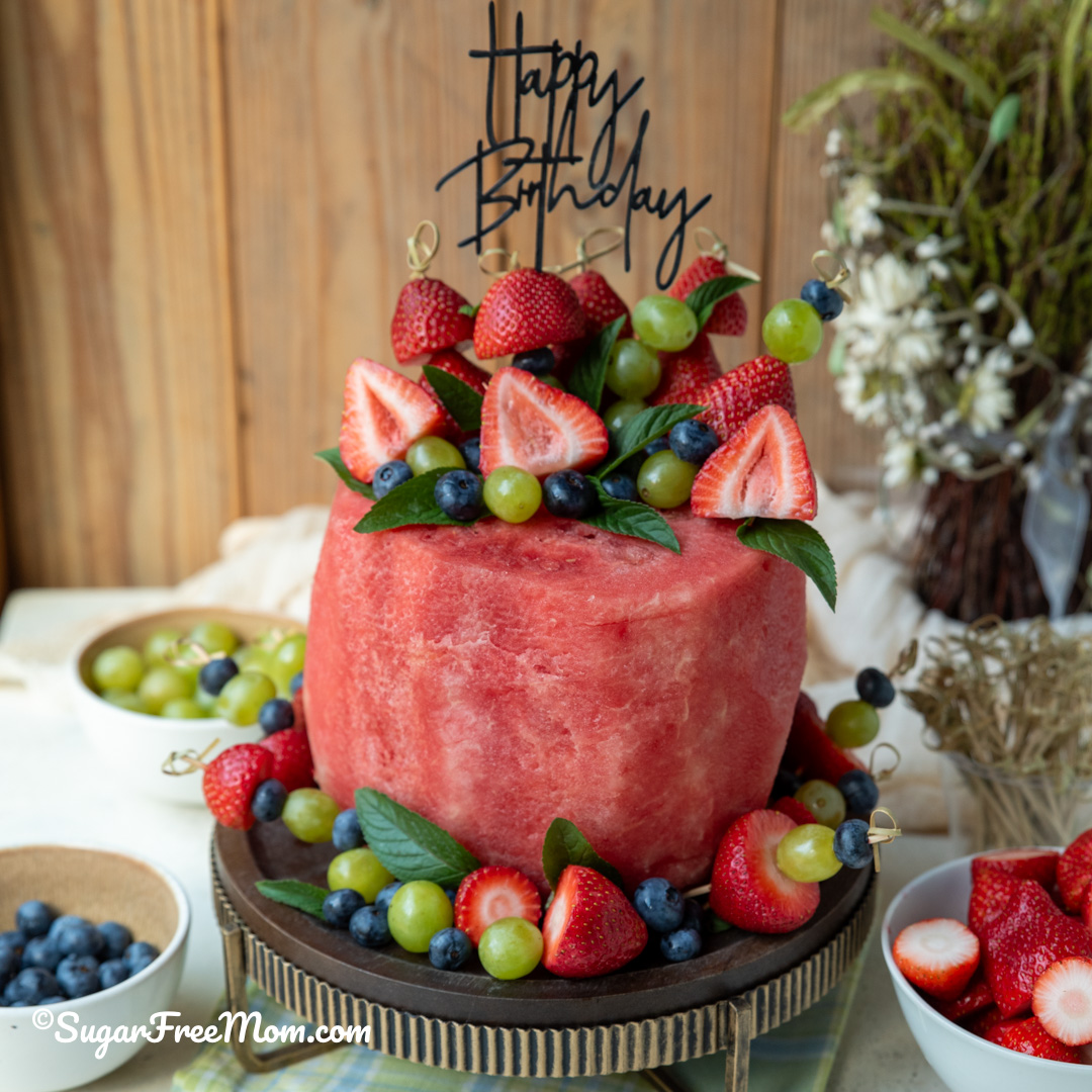 Looking for a healthy birthday cake idea? This watermelon birthday cake is made with fresh strawberries, blueberries, grapes, and mint. No baking required! Perfect for summer birthdays, baby showers, bridal showers, graduation parties, and whole-food celebrations.