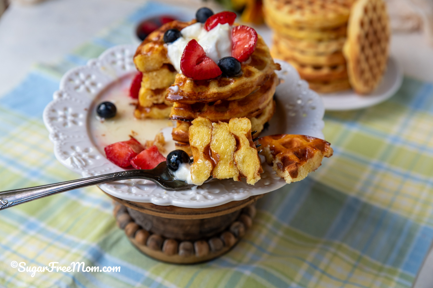horizontal image of a white plate with 4 waffles and forkful of pieces of waffle