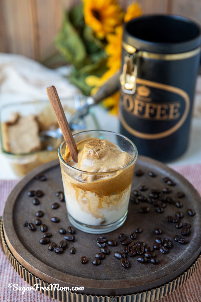 keto frozen Dalgona coffee in a glass on a tray with coffee beans surrounding it.