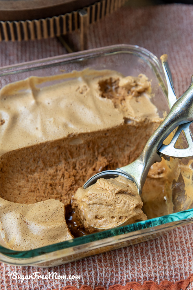 vertical image of scoop of keto frozen whipped Dalgona coffee in a glass dish