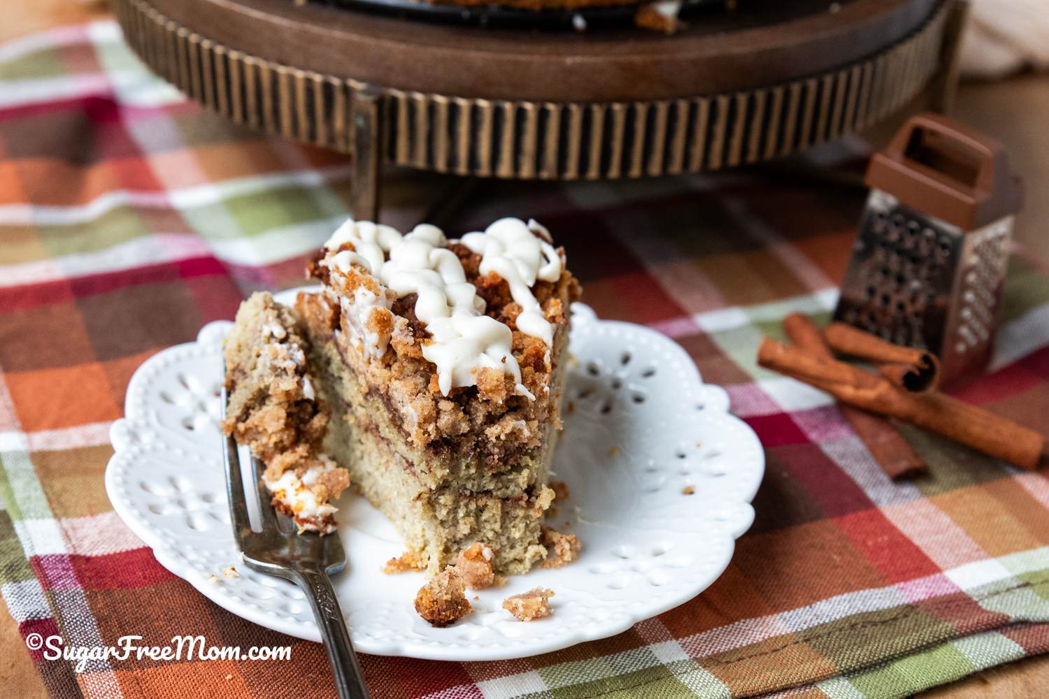horizontal image of piece of keto cinnamon roll coffee cake with a fork full on a white plate