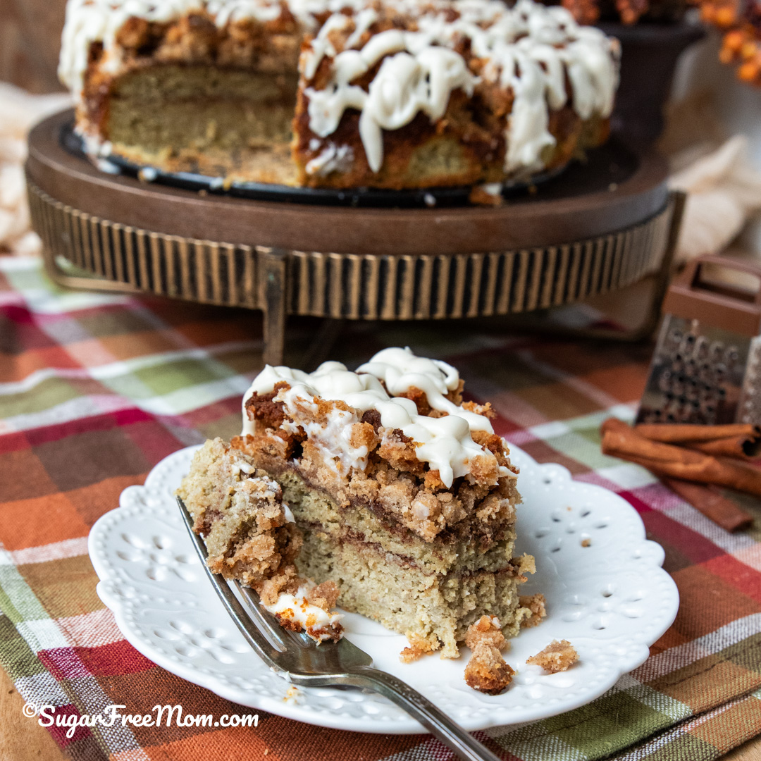 vertical image piece of low carb cinnamon roll coffee cake at an angle with piece on a fork sitting on white plate