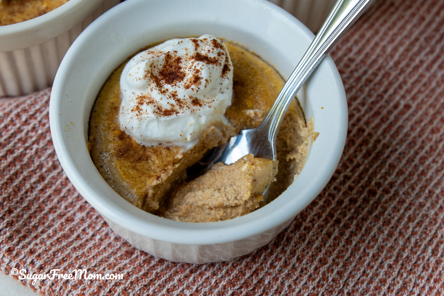 Sugar Free Keto Pumpkin Ricotta Custard topped with yogurt in a small ramekin with a spoon