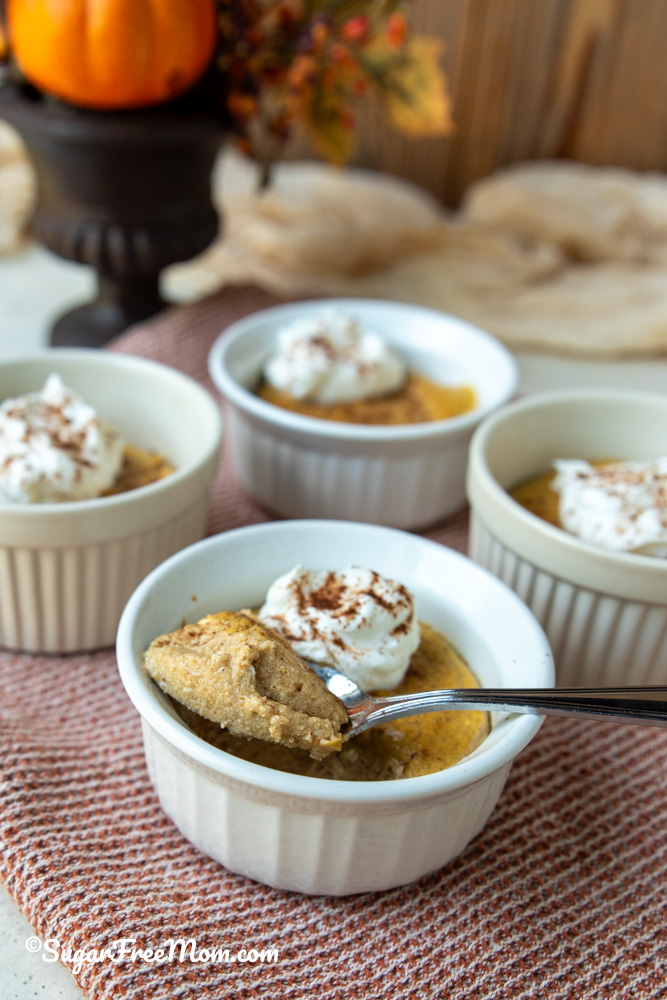horizontal image of a close up of keto pumpkin ricotta custard on a spoon resting on ramekin