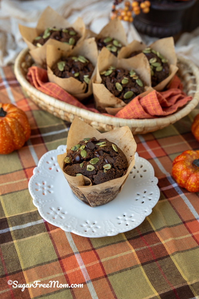 single chocolate pumpkin muffin in liner on a white plate
