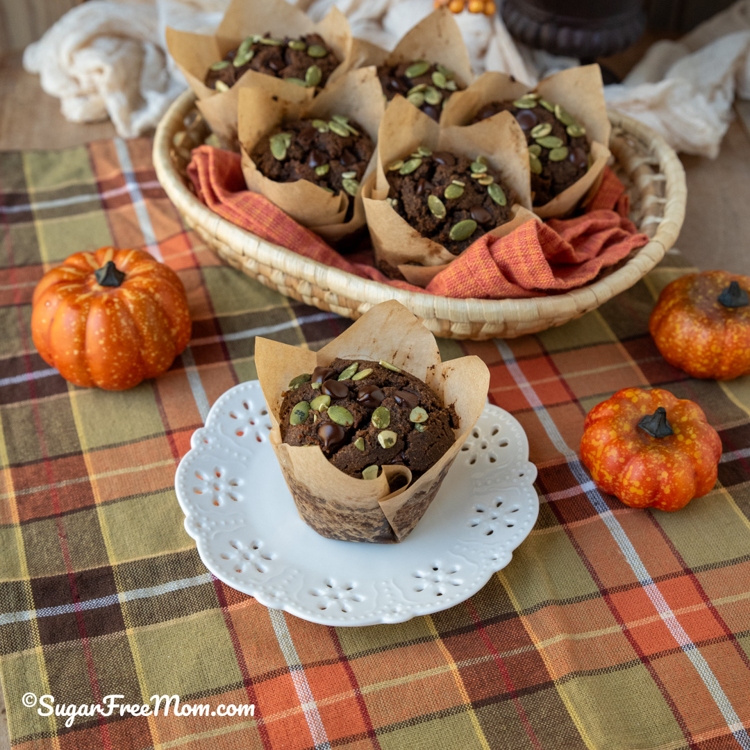horizontal image of chocolate pumpkin muffins with one a white plate and more in basket in background